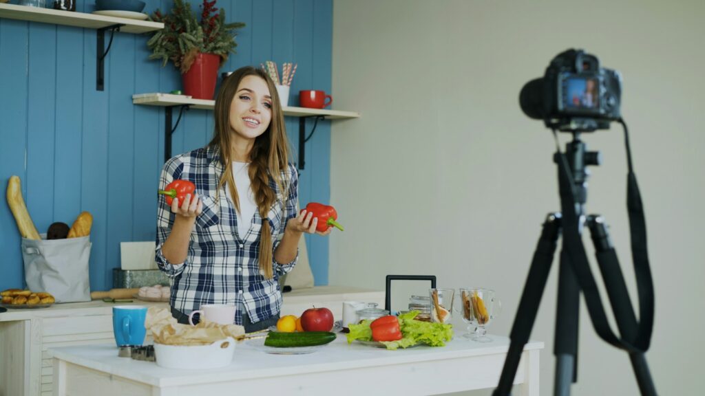 キッチンで新鮮な野菜を使った料理動画をカメラで撮影する女性