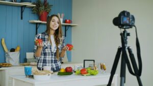 キッチンで新鮮な野菜を使った料理動画をカメラで撮影する女性